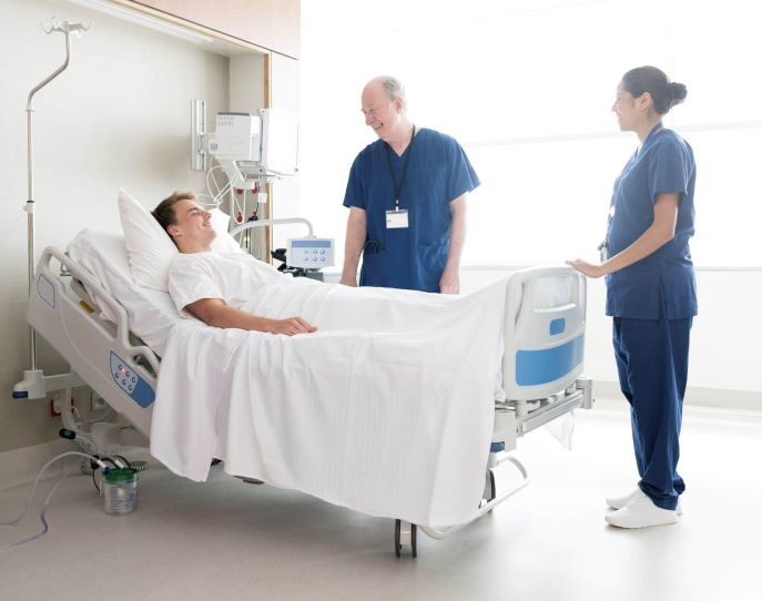 Nurses talking to a patient lying in a hospital bed