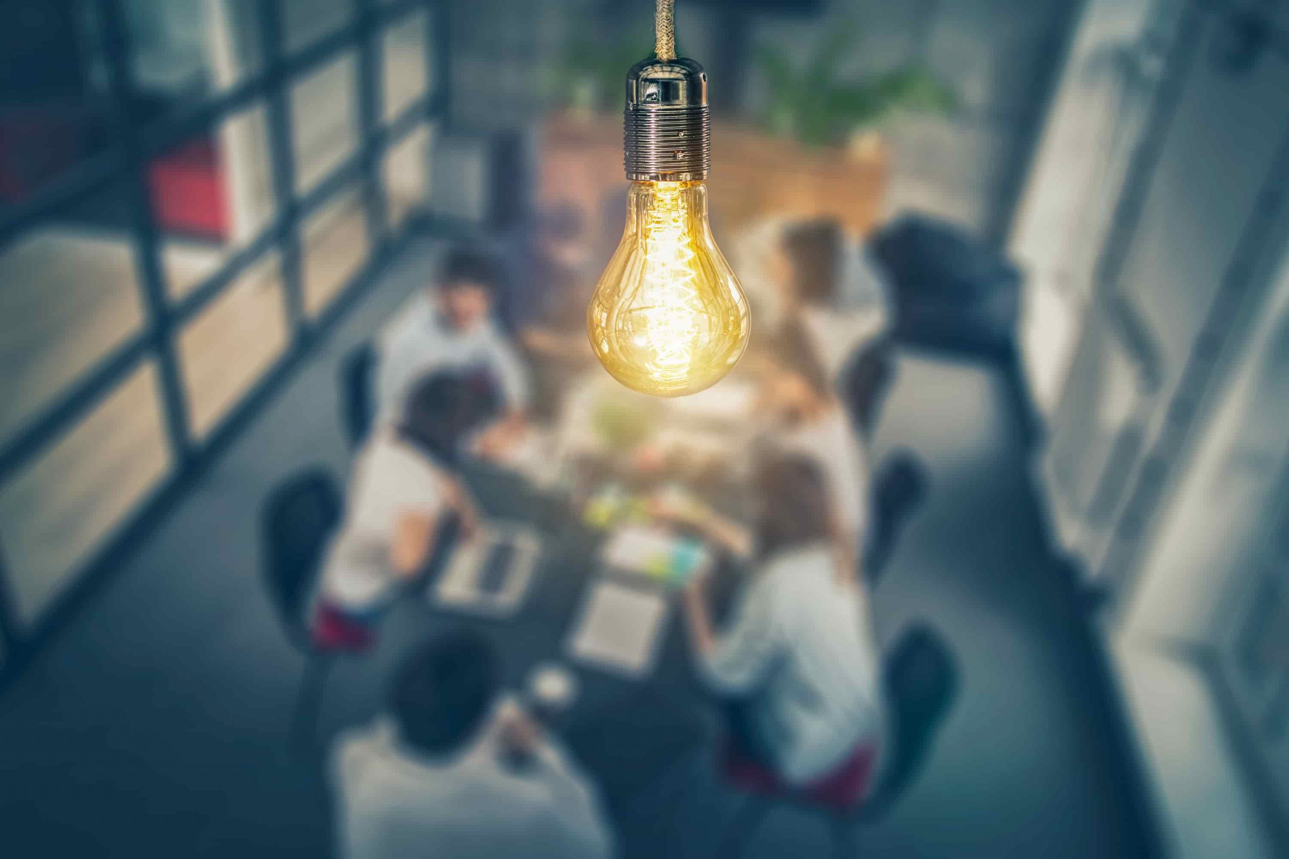 A group of people discussing something with a light bulb as the focus point